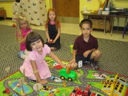 Four children playing with toys on a mat