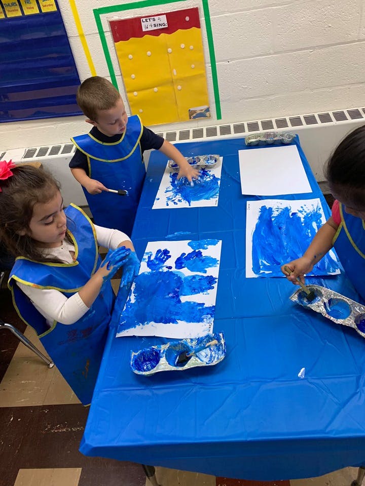 Children painting with blue paint at a table