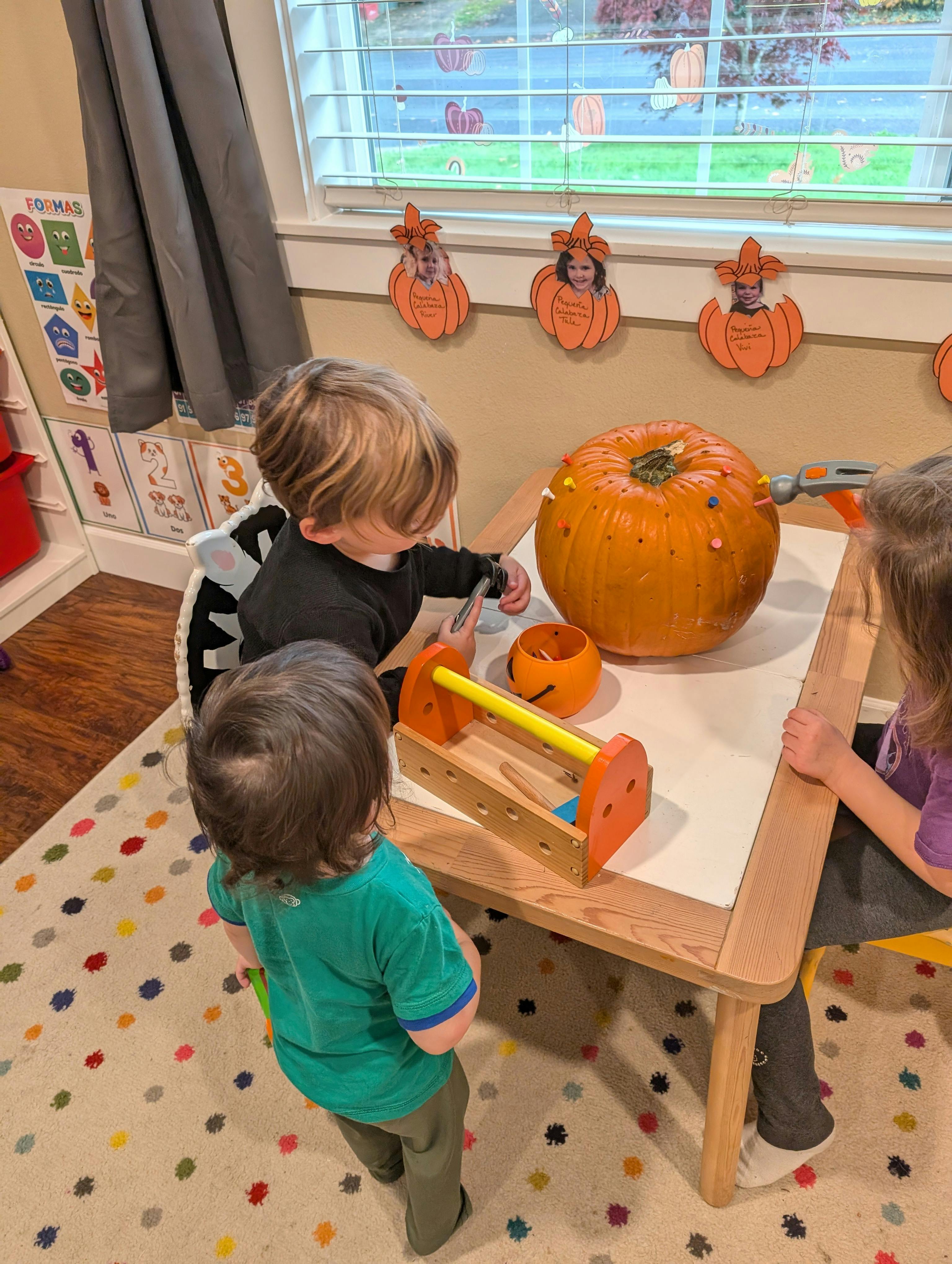 children hammering pegs into a pumpkin on a table