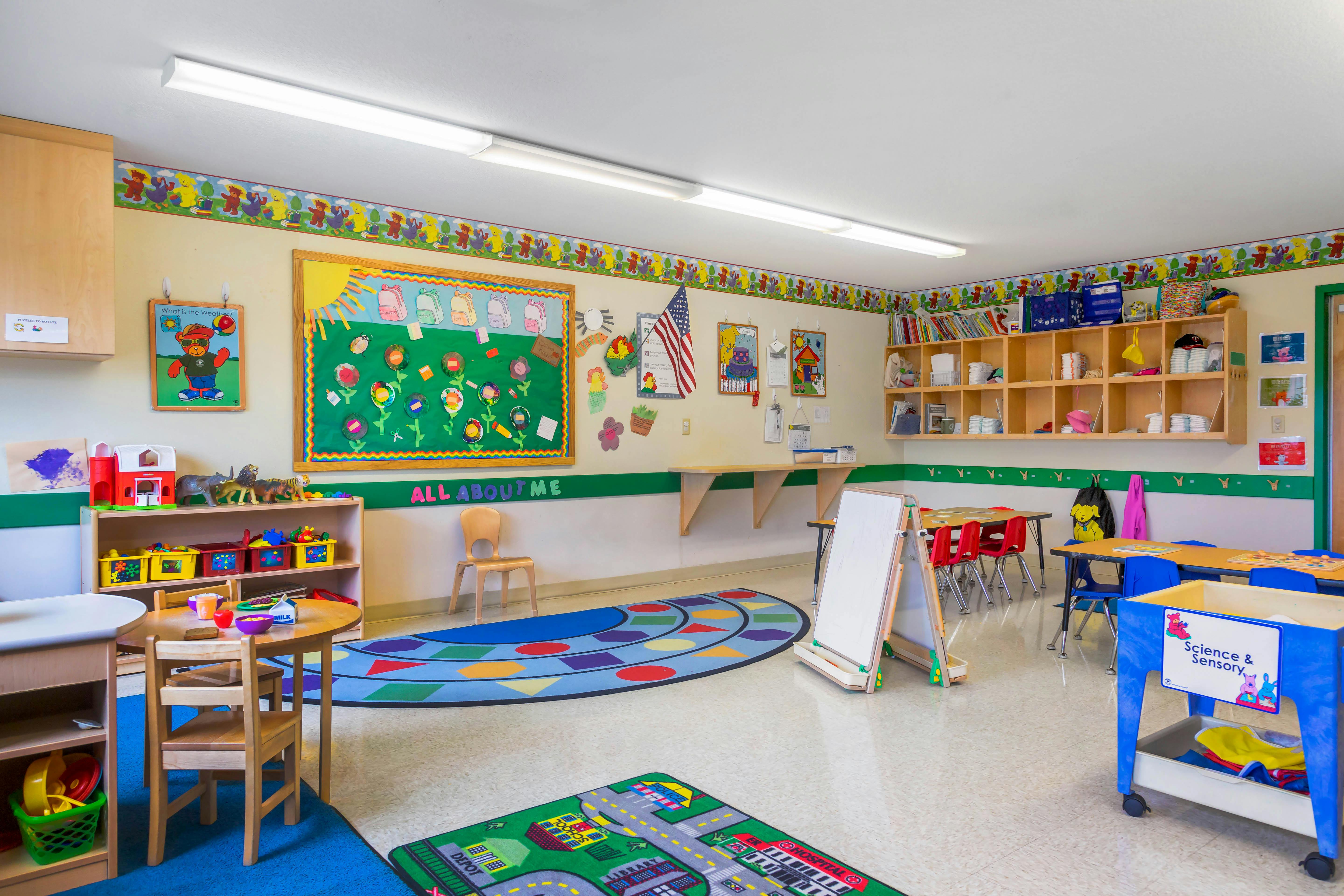 Colorful preschool classroom with various activity stations and play rugs