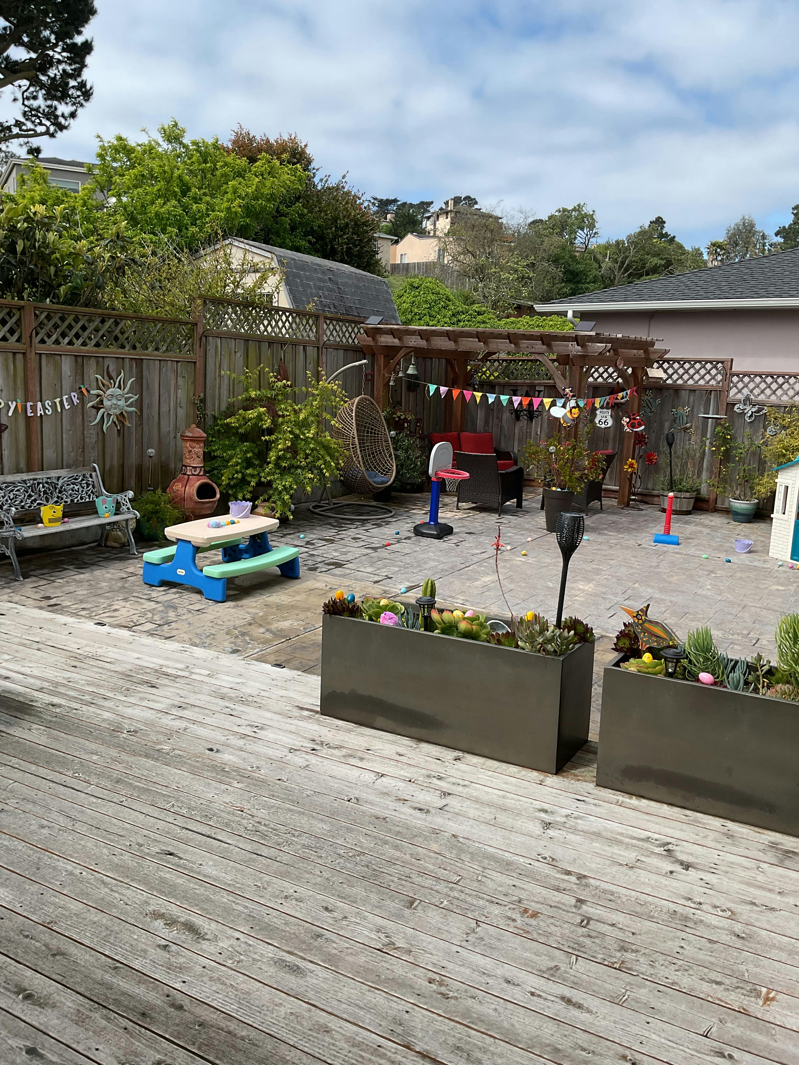 Backyard patio with wooden deck, picnic table, and planters