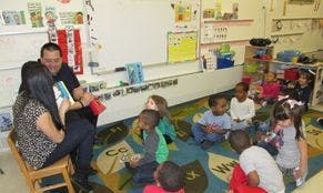 Adults reading to children in a classroom