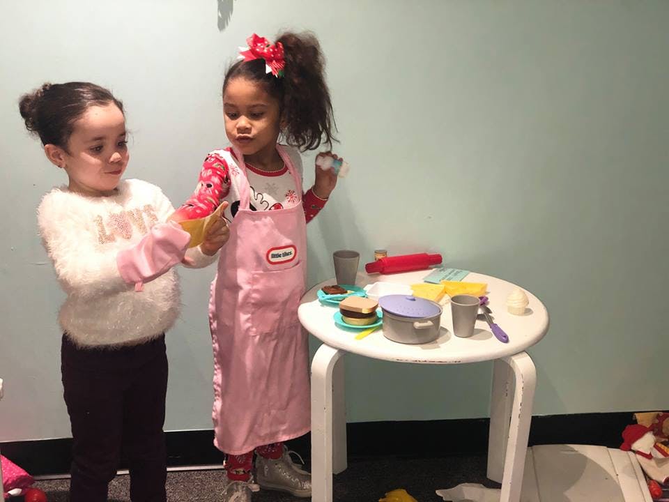 Two children playing with toy kitchen set
