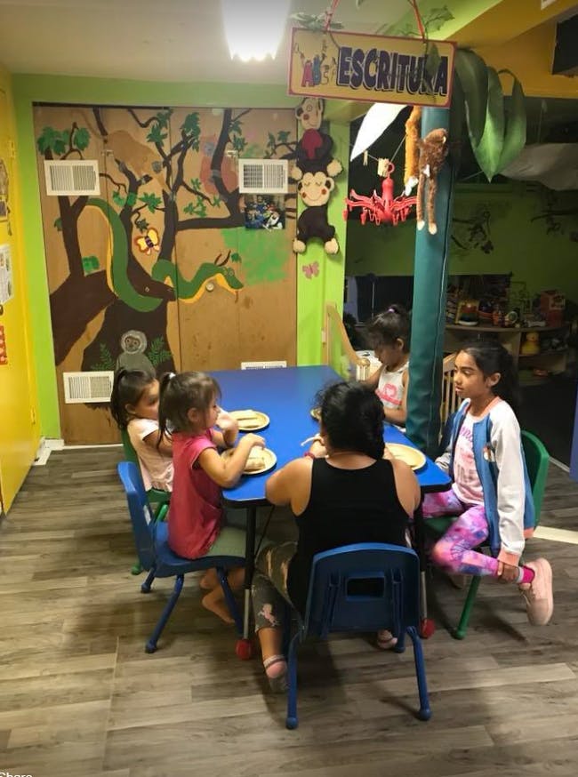 Adult and children sitting at a blue table in a classroom