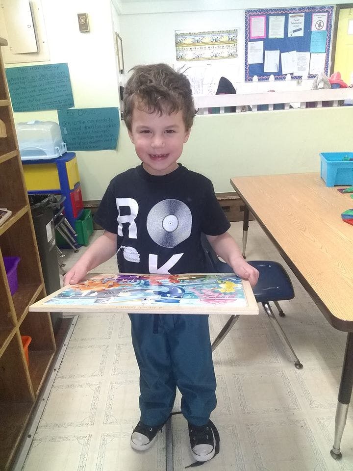 Child holding a colorful puzzle in a classroom