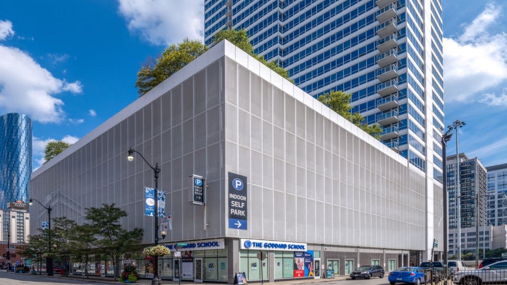 Modern building with a parking sign and storefronts at its base