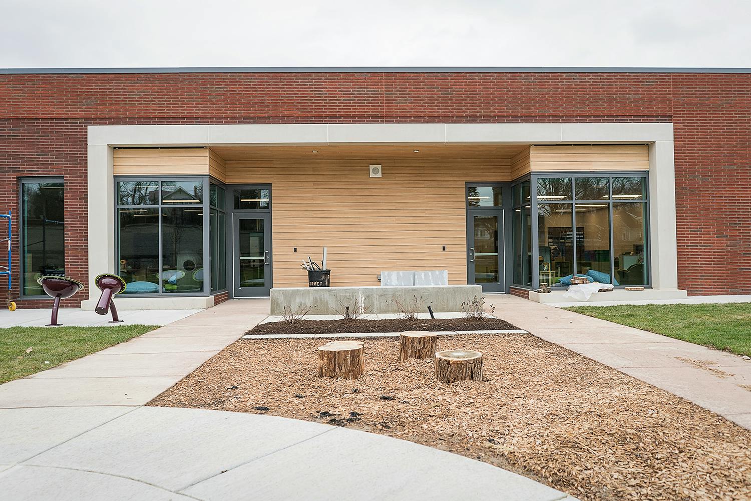 Exterior of a building with brick and wood siding, large windows, and a walkway