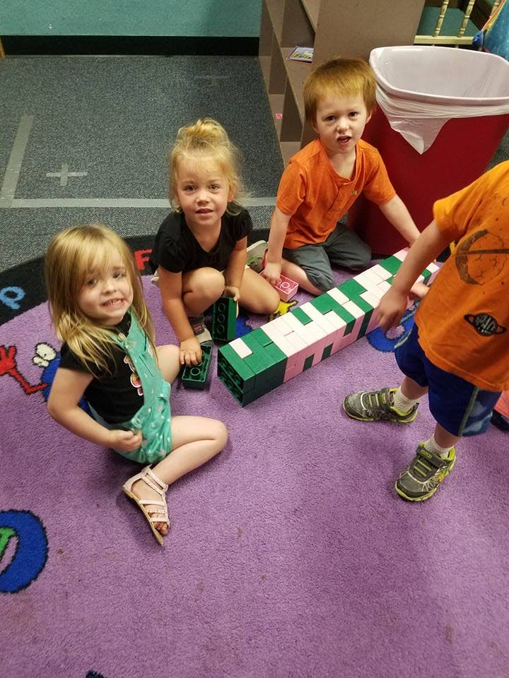 Children playing with large building blocks on a purple carpet