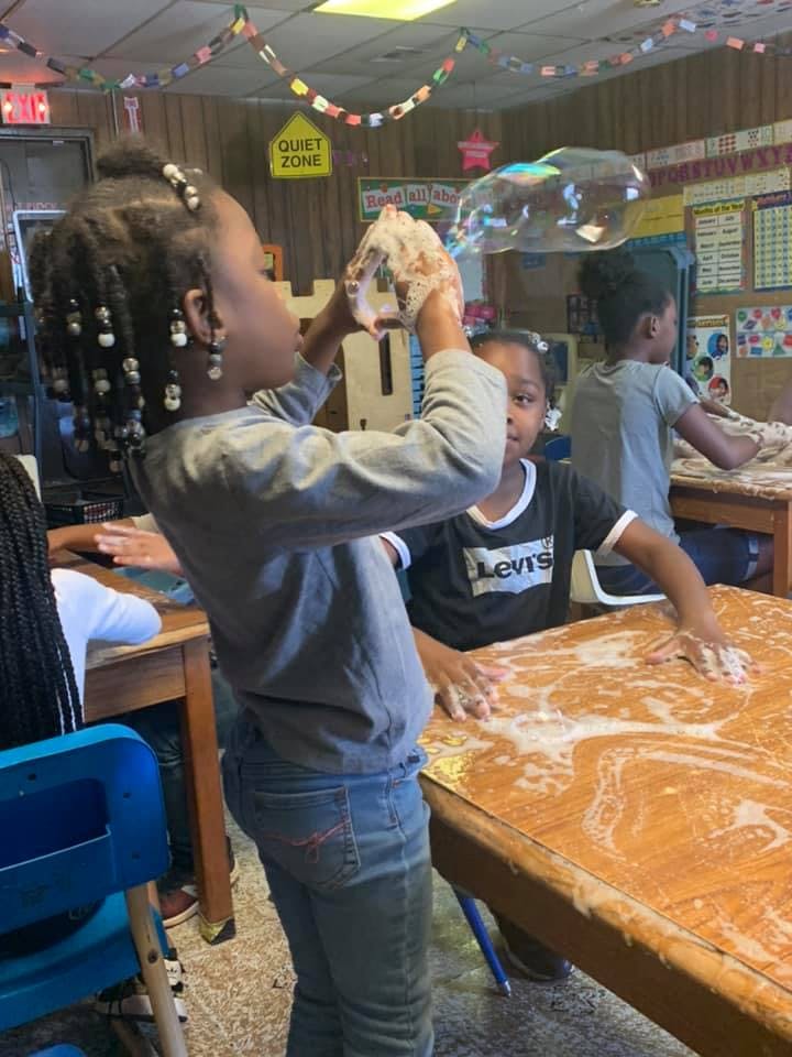 Child blowing bubbles in a classroom