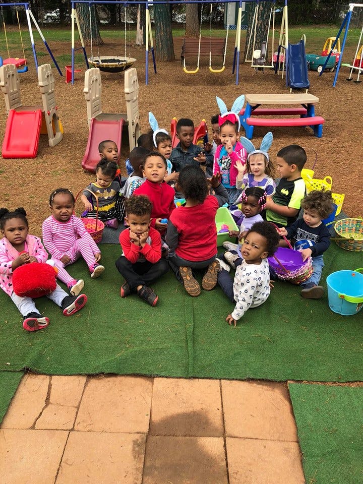 Group of children sitting on a green mat at a playground