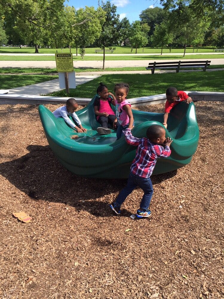 Children playing on a green boat-shaped playground structure