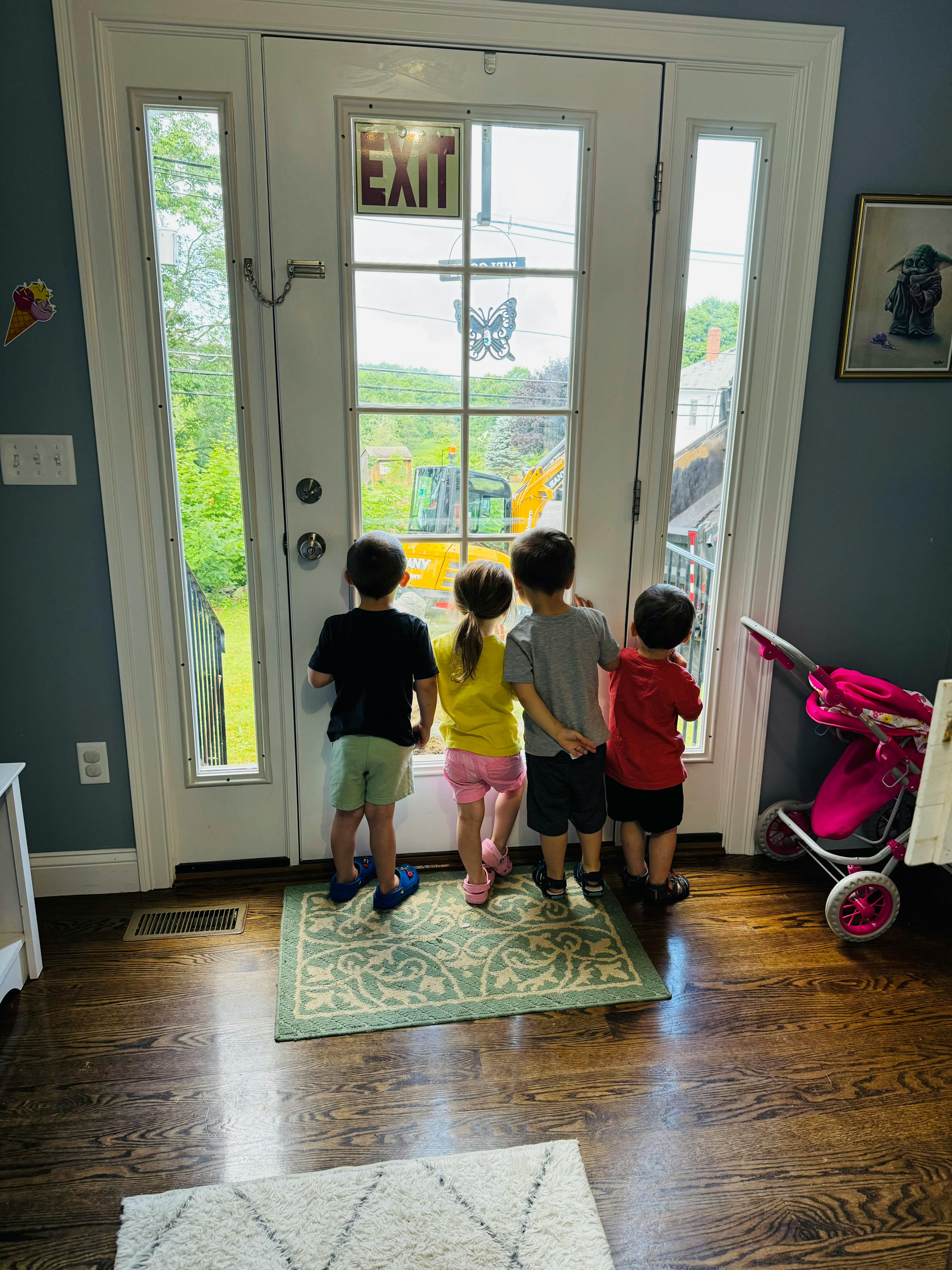 Four children looking out a glass door with an "EXIT" sign