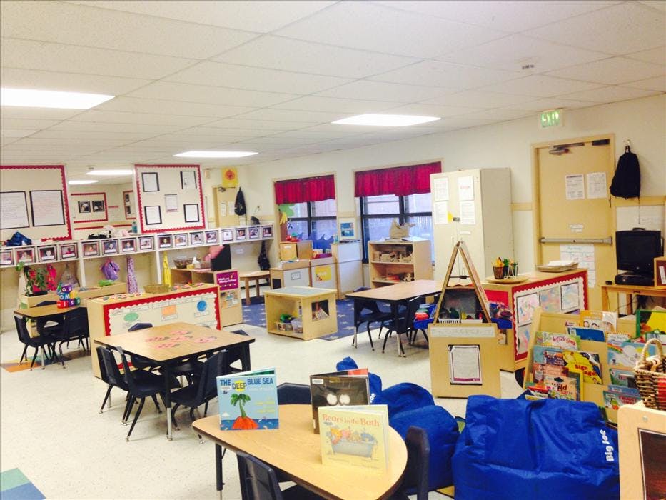 Empty classroom with small tables, chairs, and learning materials