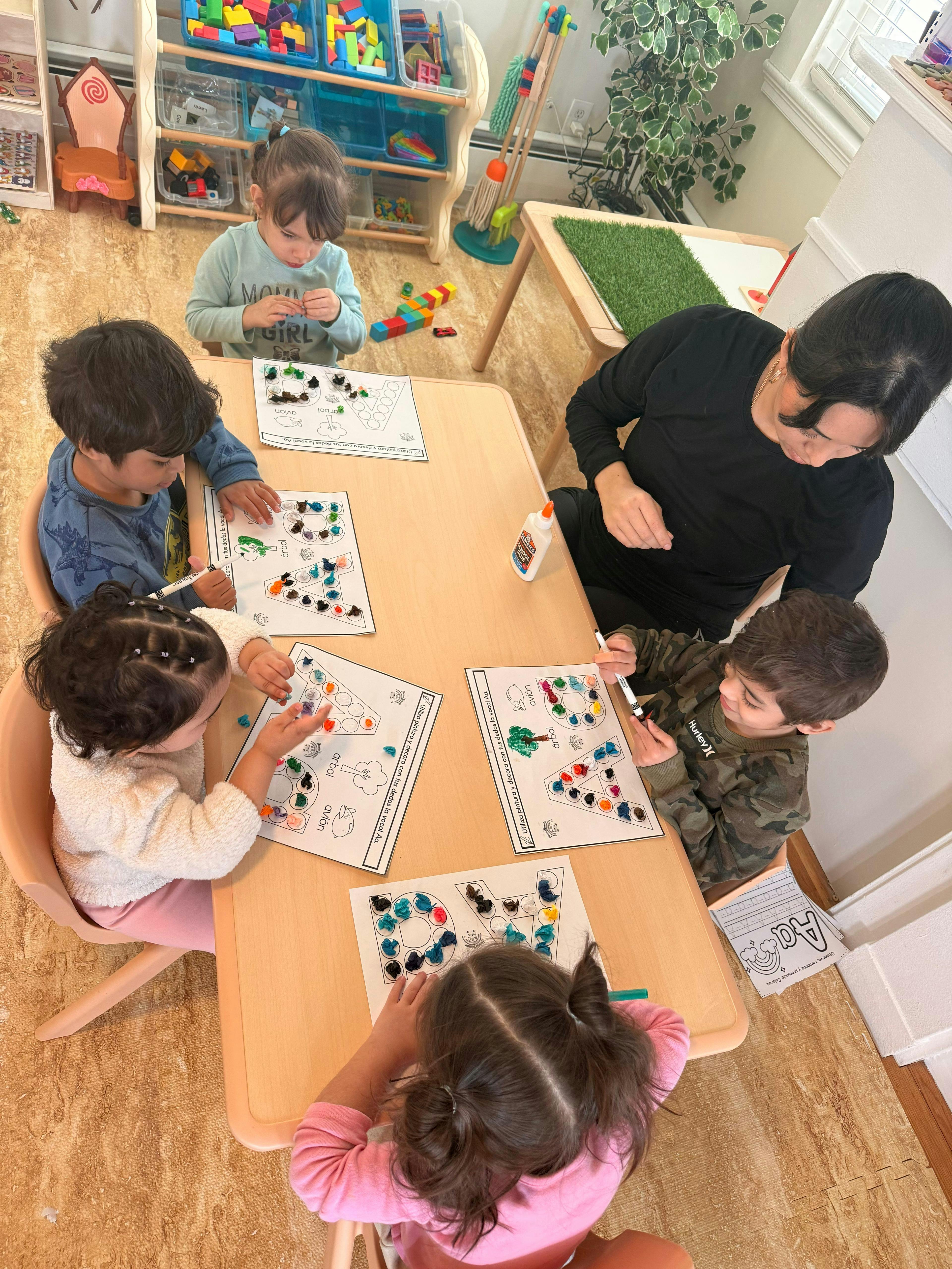 Teacher and four children doing a craft activity in a classroom