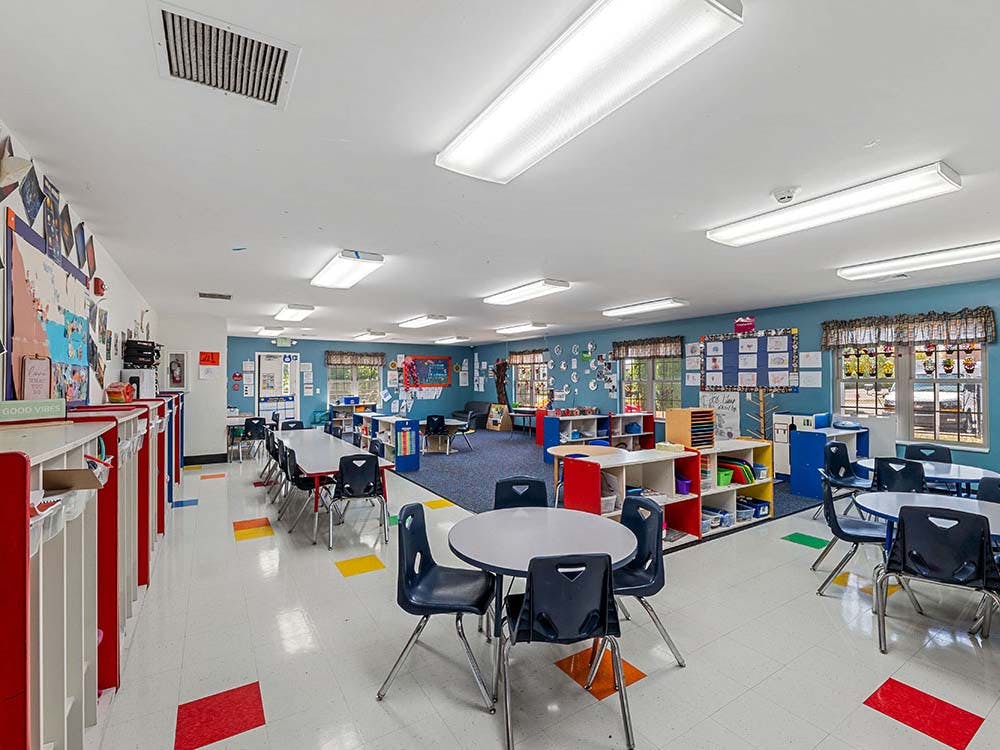 Empty classroom with small tables and chairs, and colorful storage units