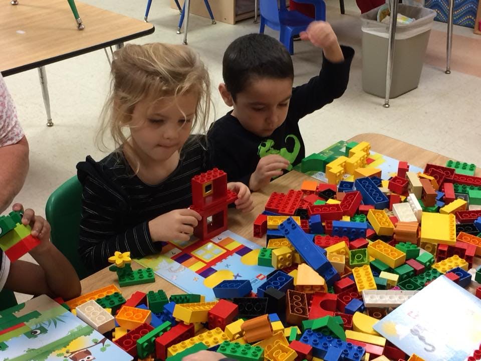 Two children playing with colorful building blocks at a table