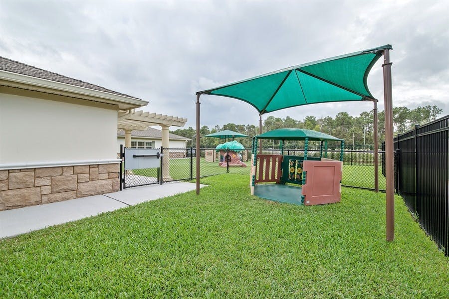 Outdoor playground with green shade structures and a sandpit