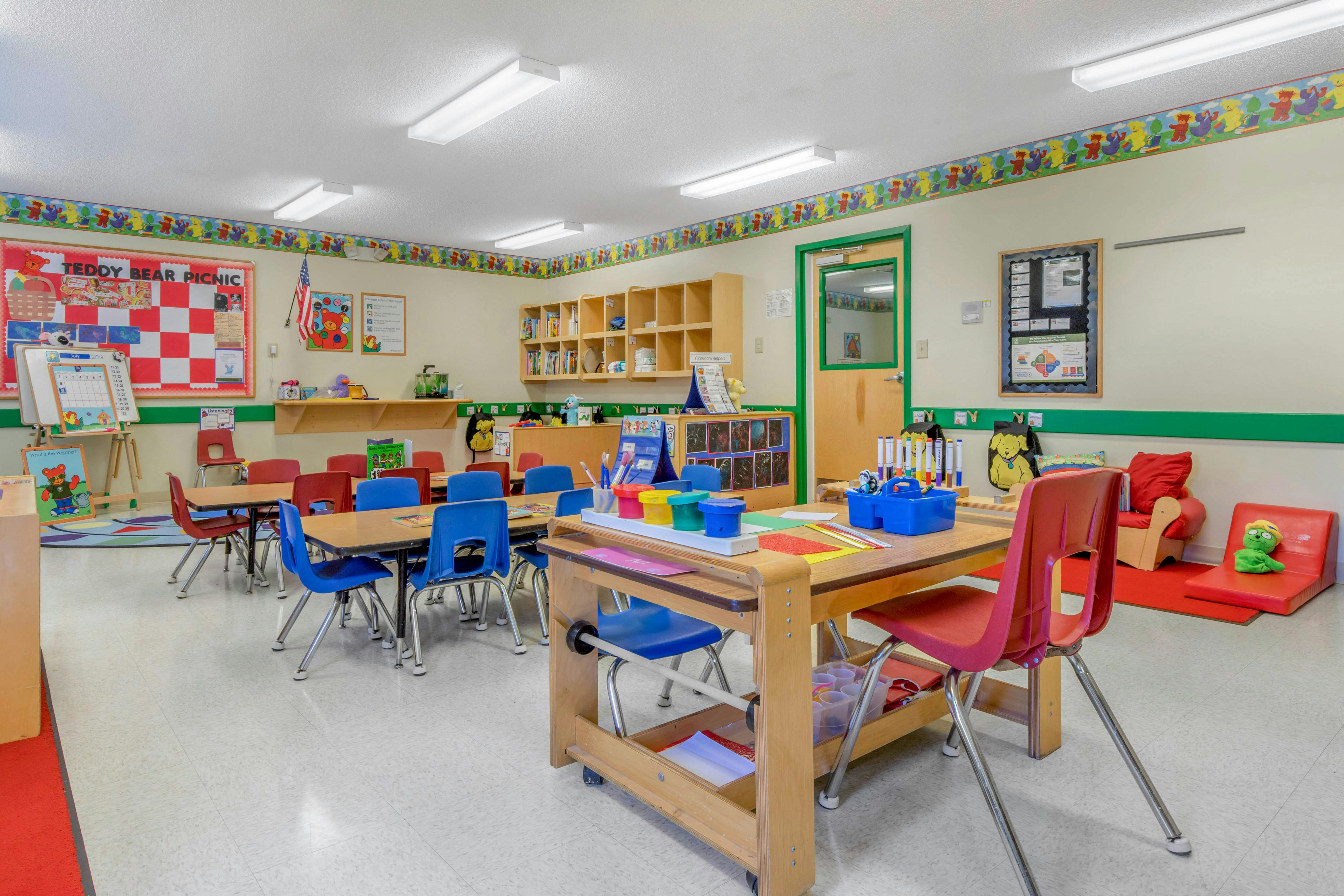 An empty early childhood classroom with small tables and chairs