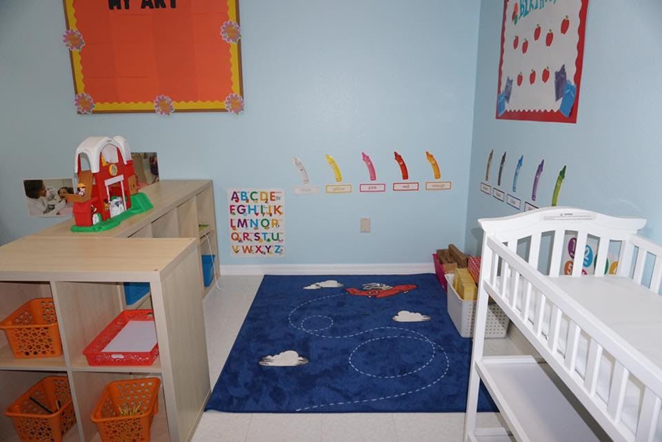 Playroom with blue rug, toy barn, and changing table