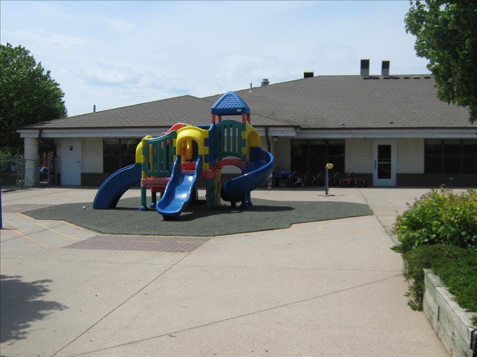 Playground with colorful slides and climbing structures in front of a building