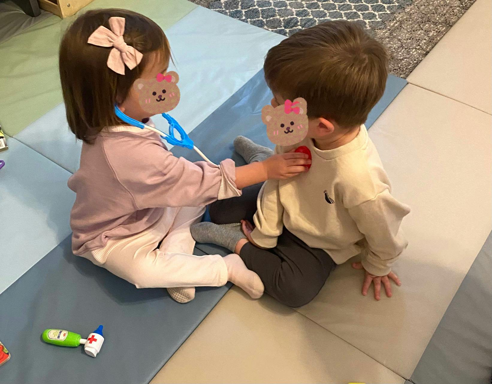 Child playing doctor with another child using a toy stethoscope