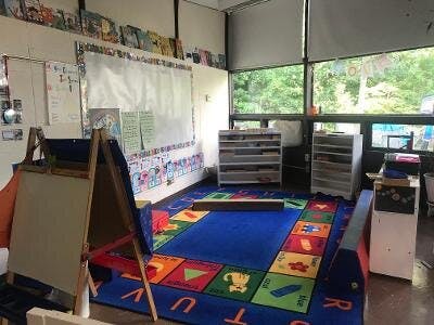 Classroom with a colorful alphabet rug, easels, and storage shelves