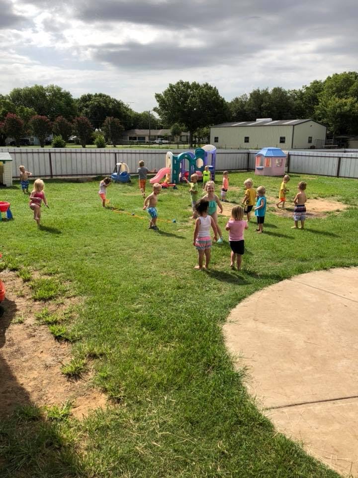 Children playing outdoors in a grassy area with playground equipment