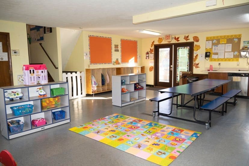 Playroom with colorful rug, storage shelves, and tables