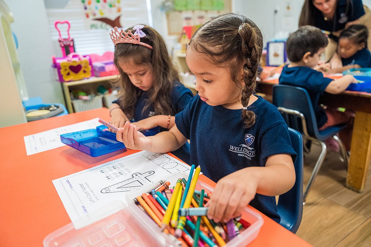 Two children coloring at a table in a classroom