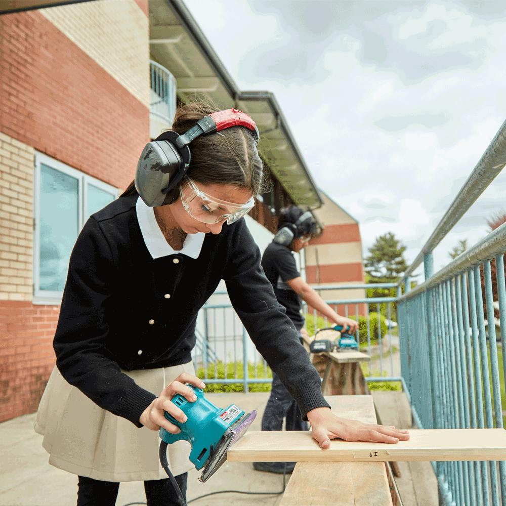 Teen using a power sander on a piece of wood