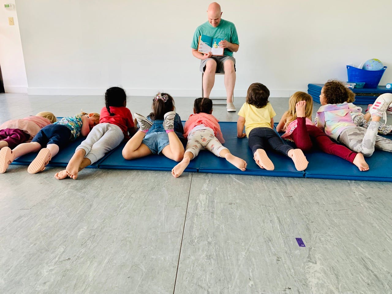 Person reading to a group of children lying on mats