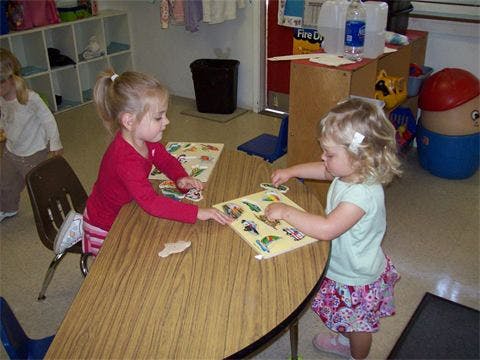 Two children playing with puzzles at a table
