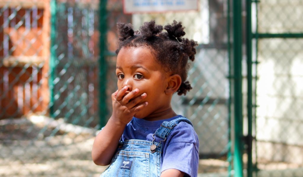 Child with hand over mouth