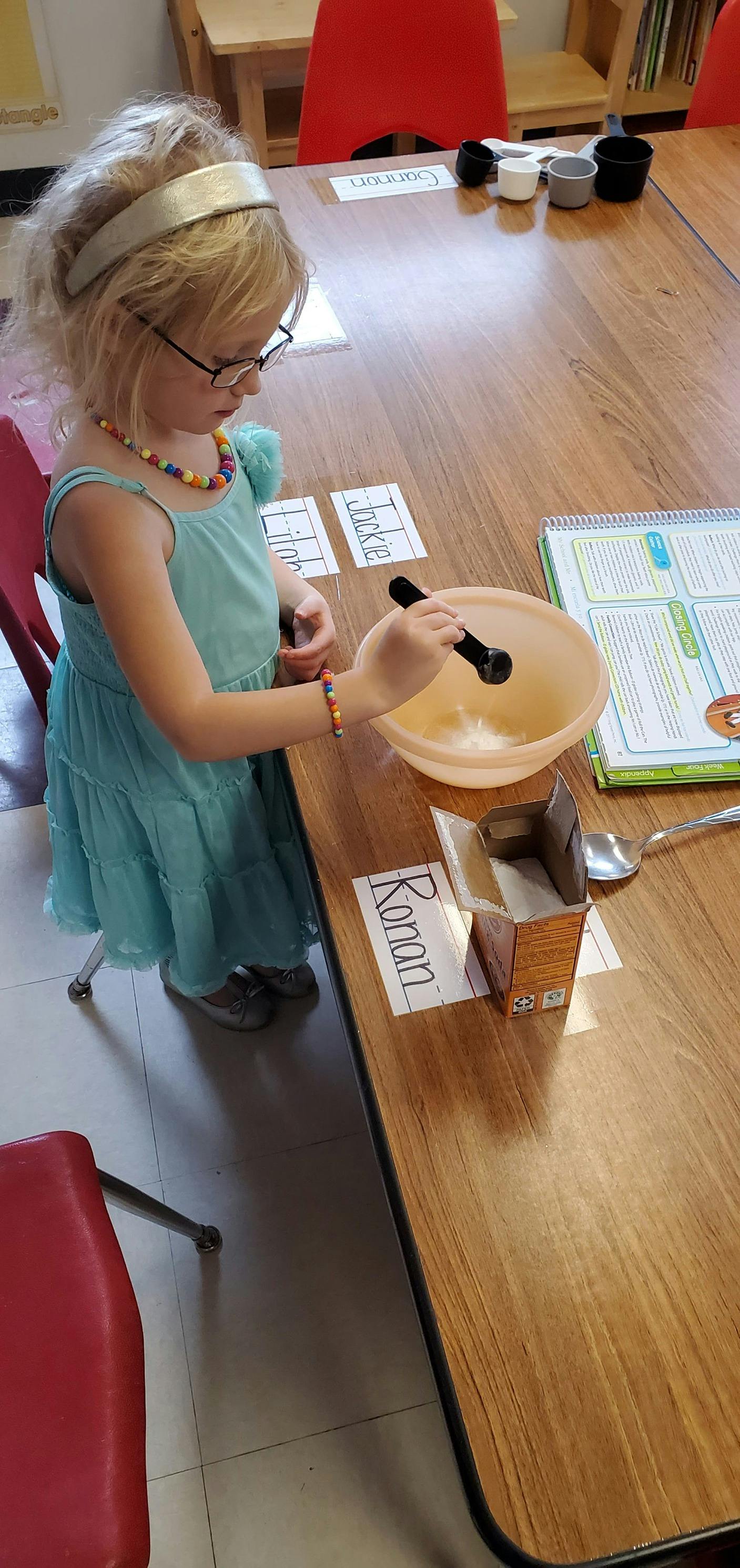 Child in glasses stirring a bowl on a table