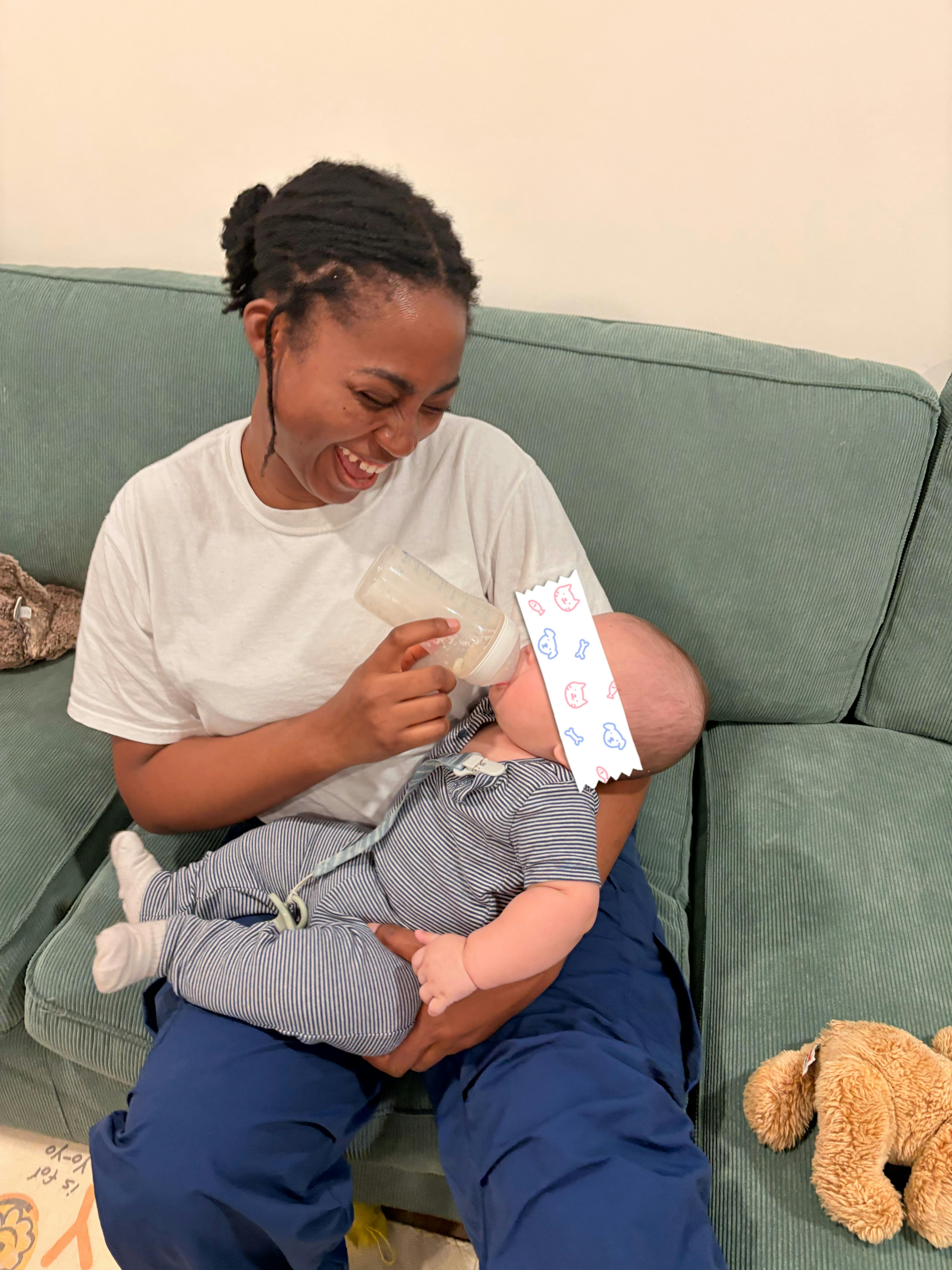 Person holding and bottle feeding a child on a couch