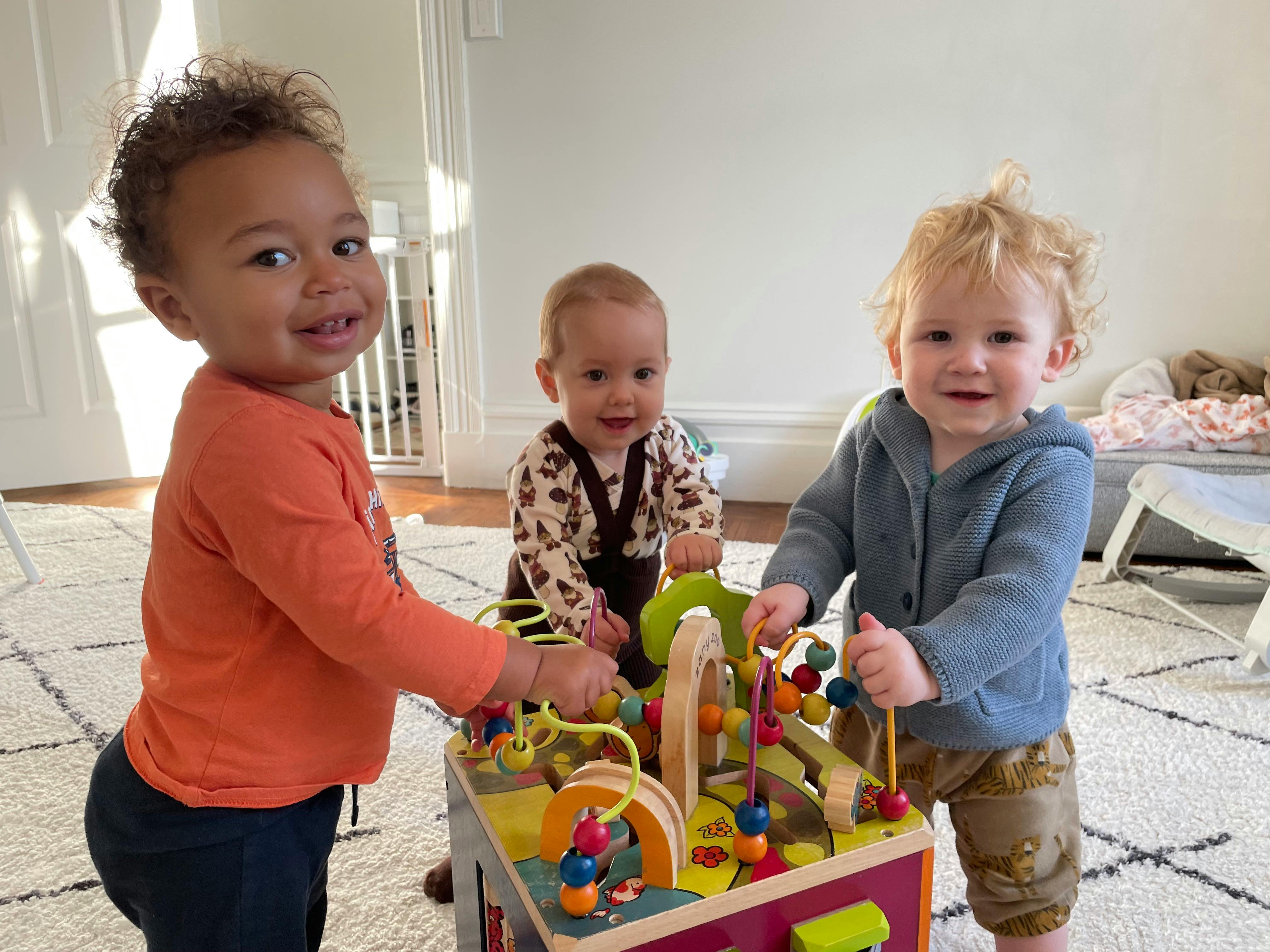 Three children playing with a bead maze toy