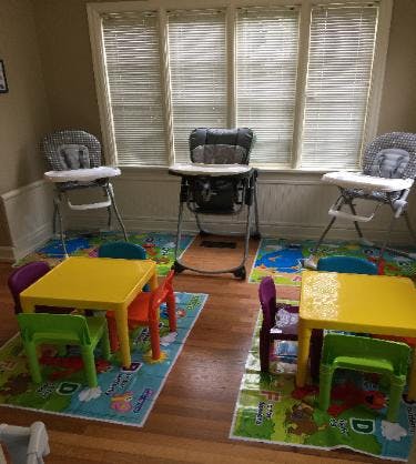 Three high chairs and two child-sized tables with chairs on playmats