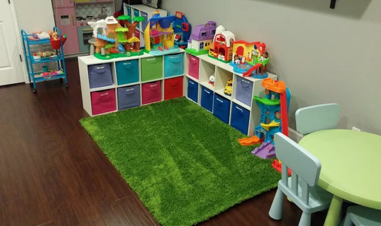 Playroom with toy storage shelves, a green rug, and a small table with chairs