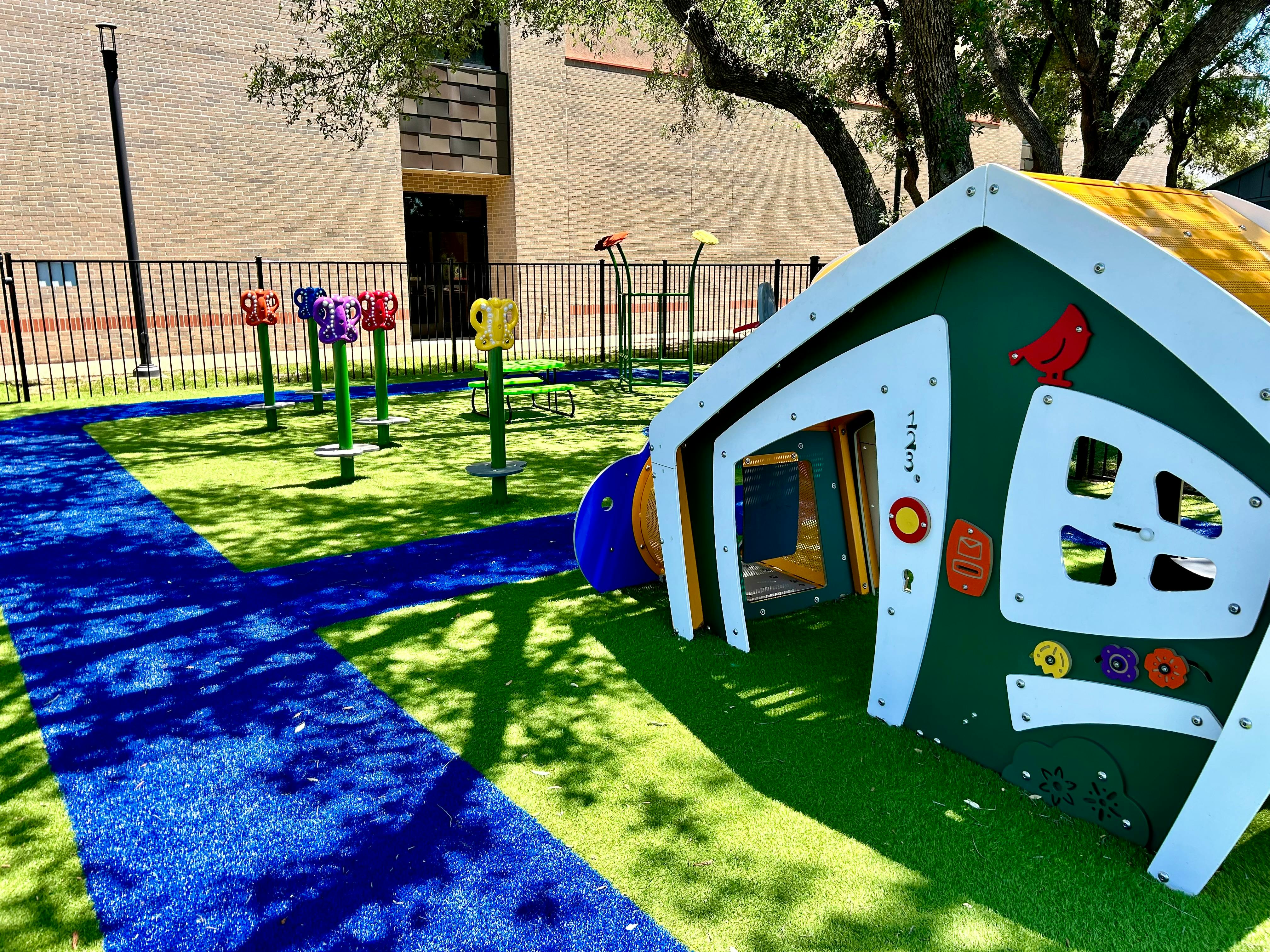 Playground with a small playhouse and spring riders on artificial turf