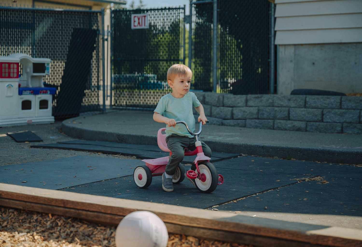 Child riding a pink tricycle outdoors