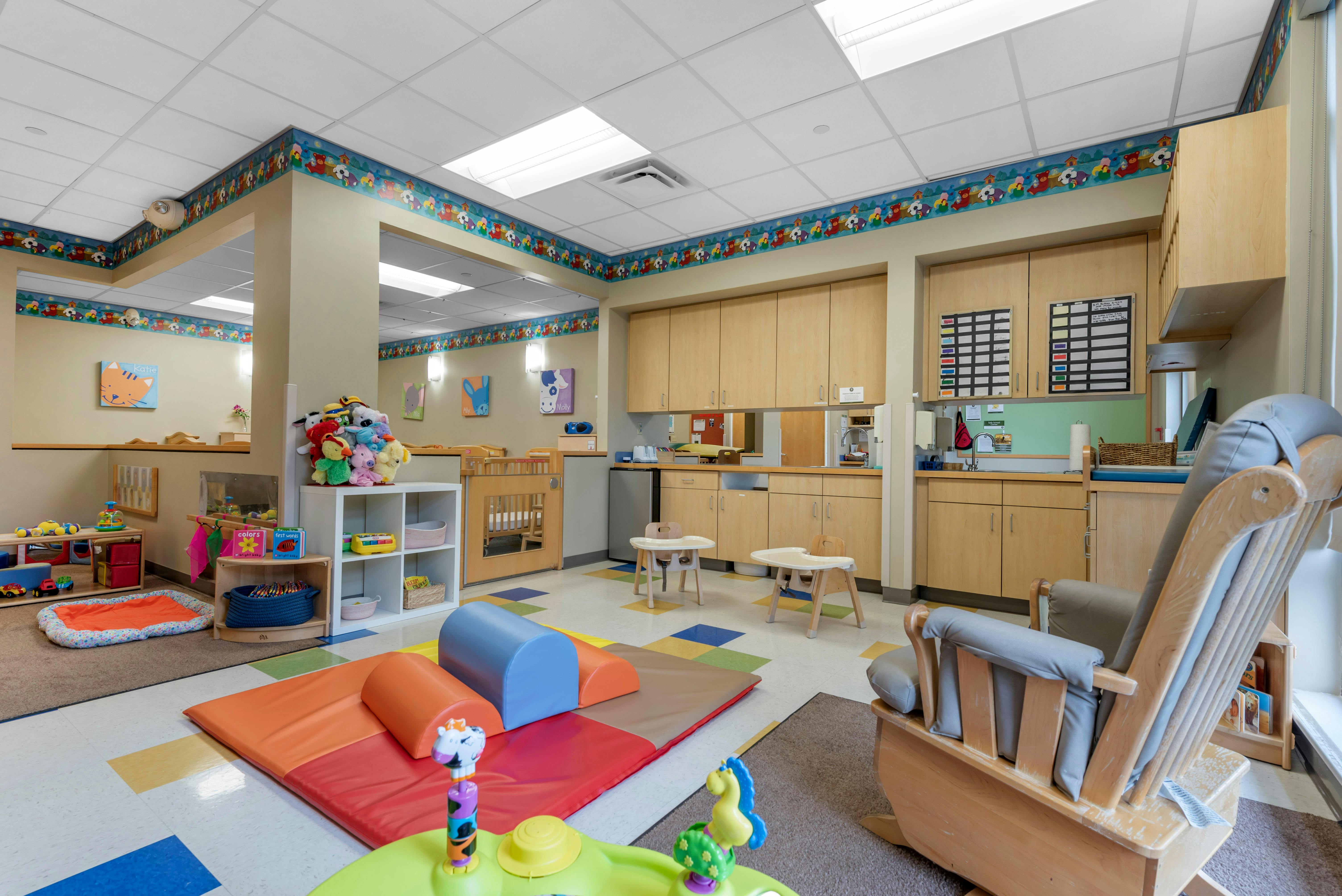 Playroom with soft play equipment, small tables, and a rocking chair