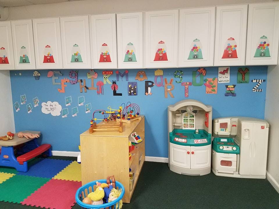 Playroom with toy kitchen, wooden shelf, and alphabet letters on the wall