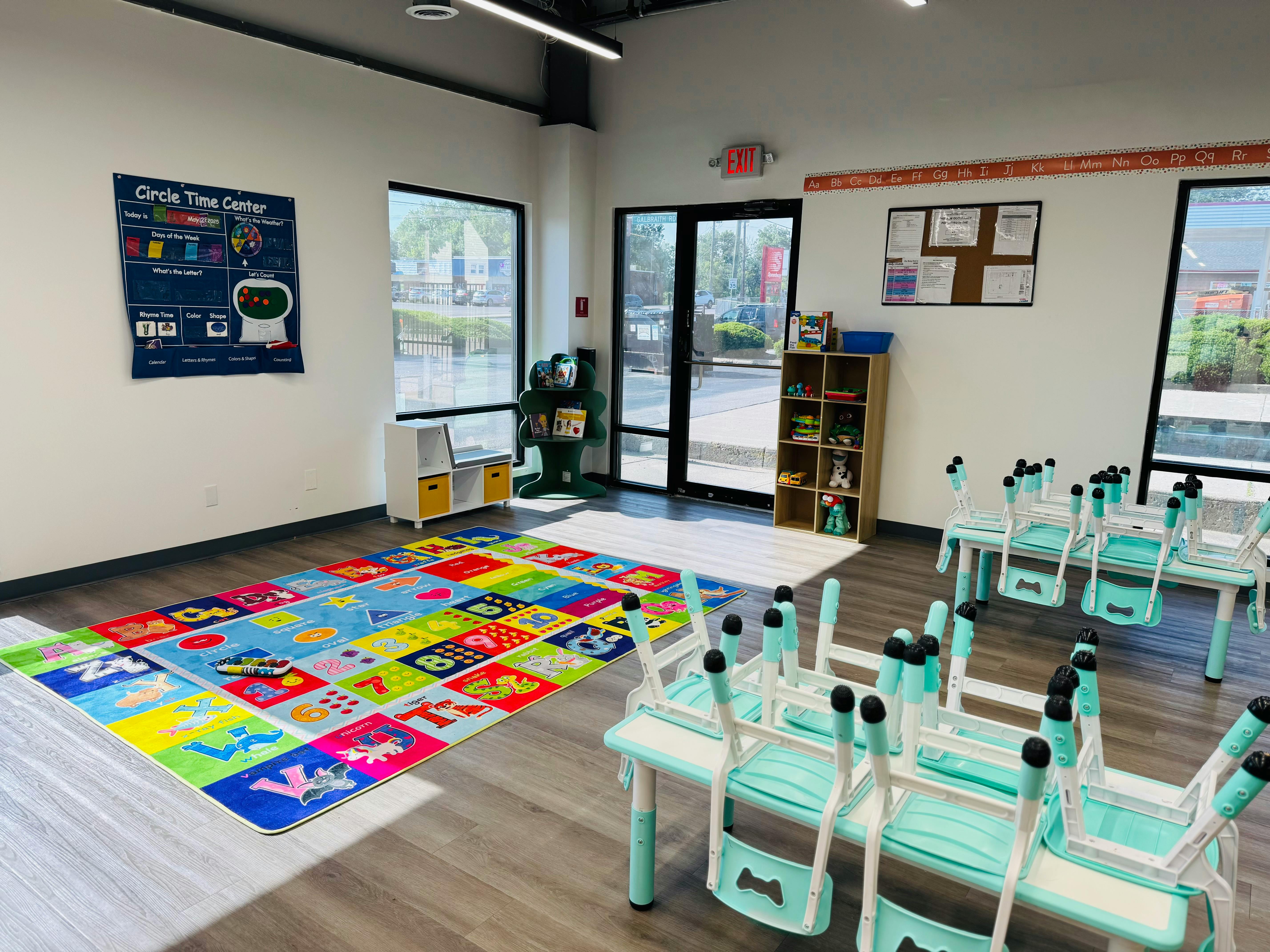 Classroom with colorful alphabet rug and small tables with chairs