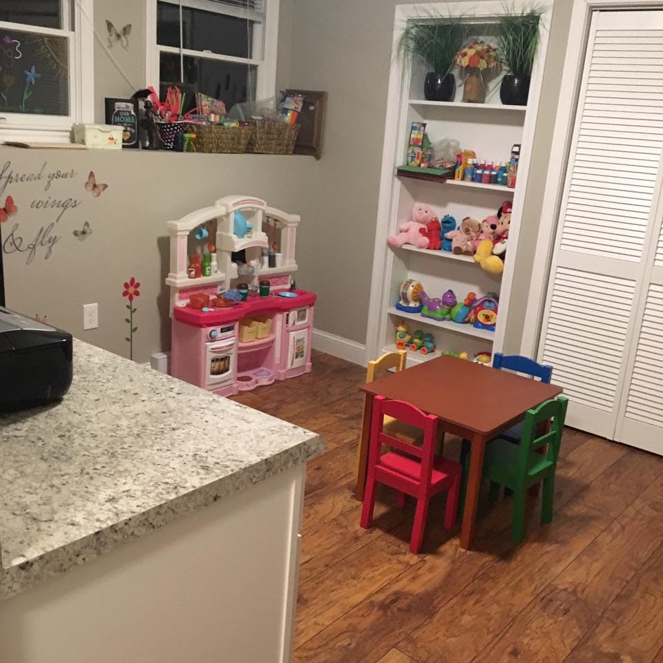 Playroom with toy kitchen, small table and chairs, and shelves of toys