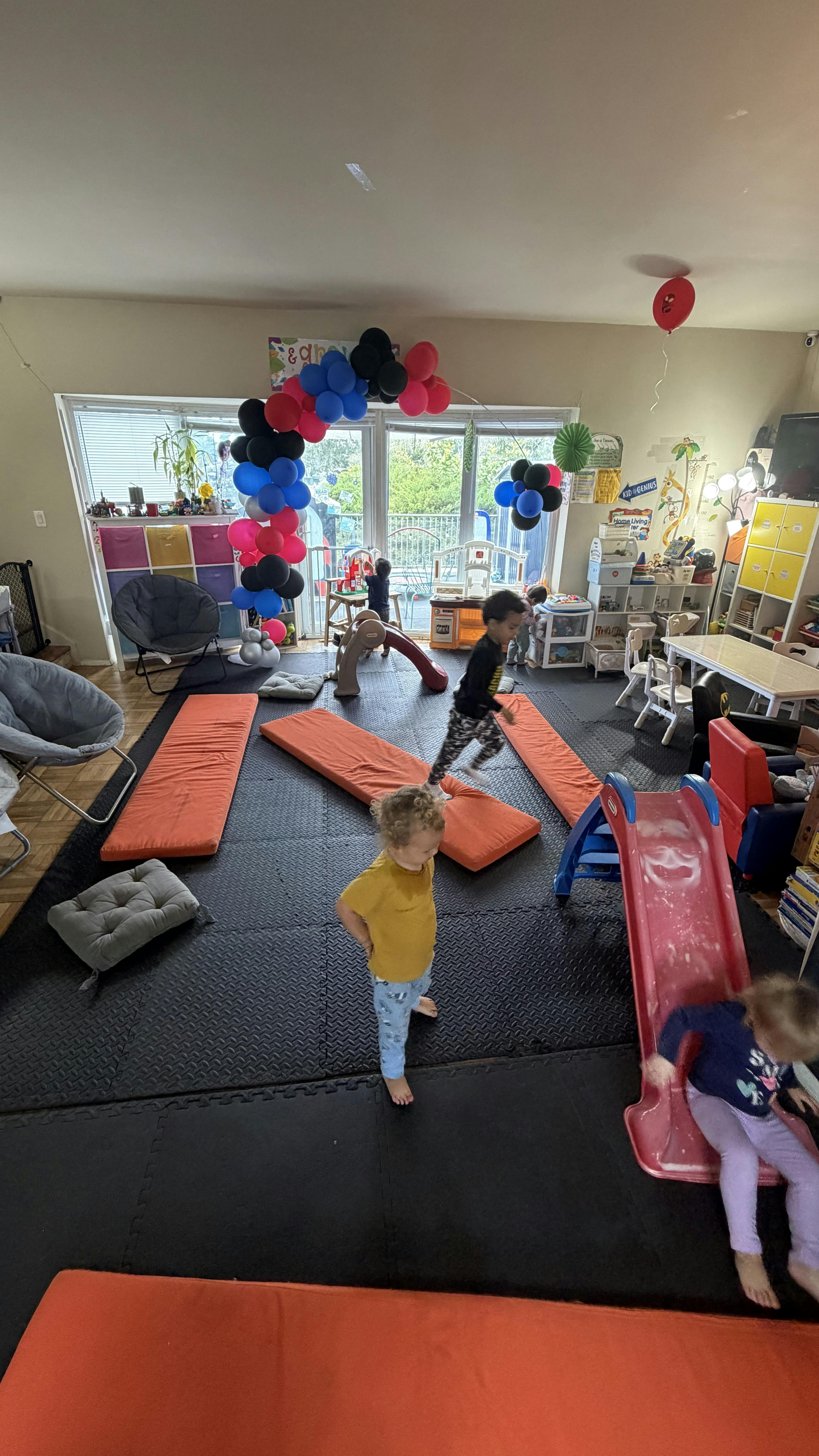 Children playing in a room with a balloon arch and play equipment