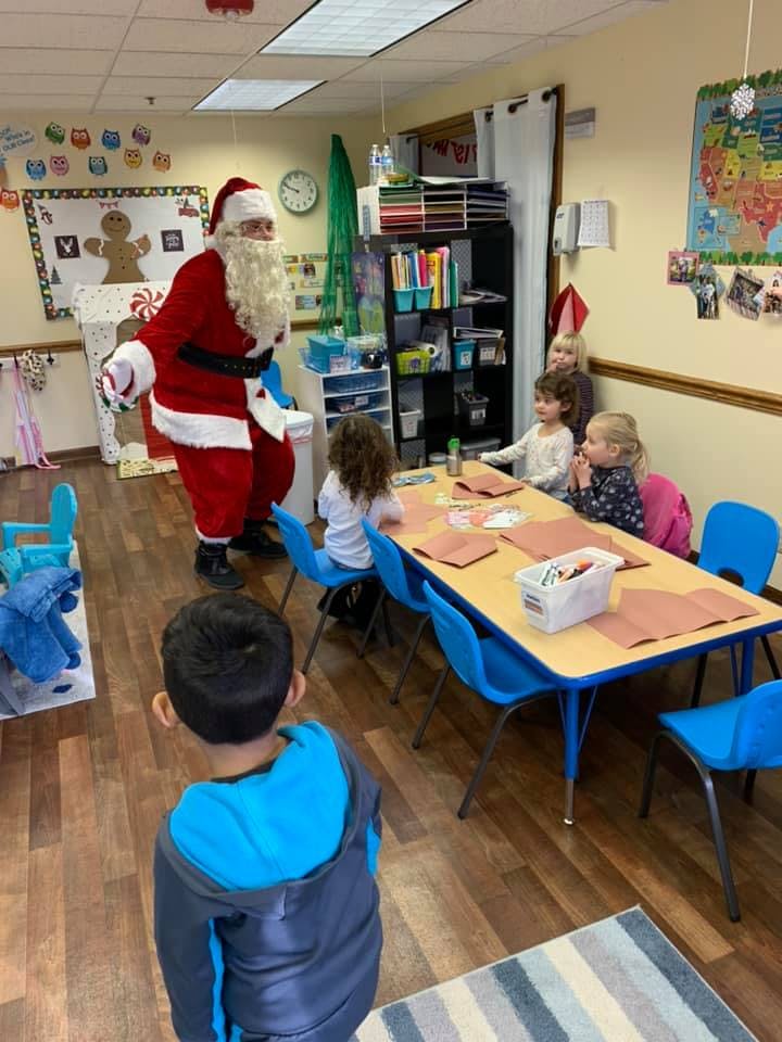 Person dressed as Santa Claus interacting with children in a classroom