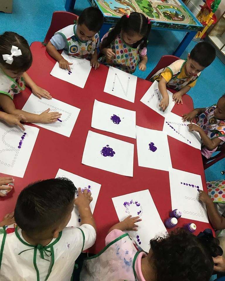Children doing finger painting at a red table
