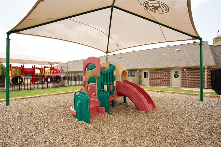 Playground with slides and climbing structures under a shade canopy