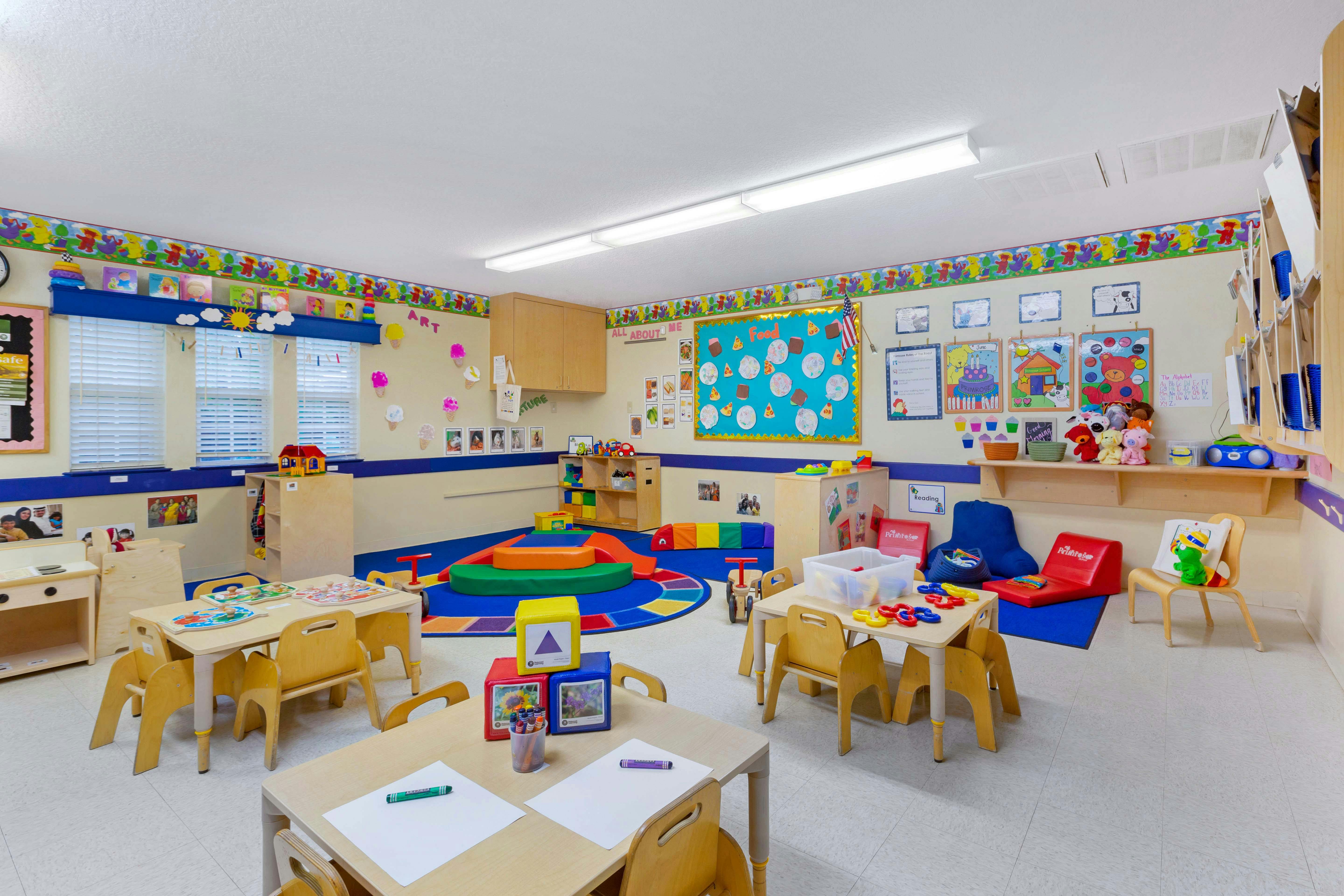 An empty early childhood classroom with small tables and chairs