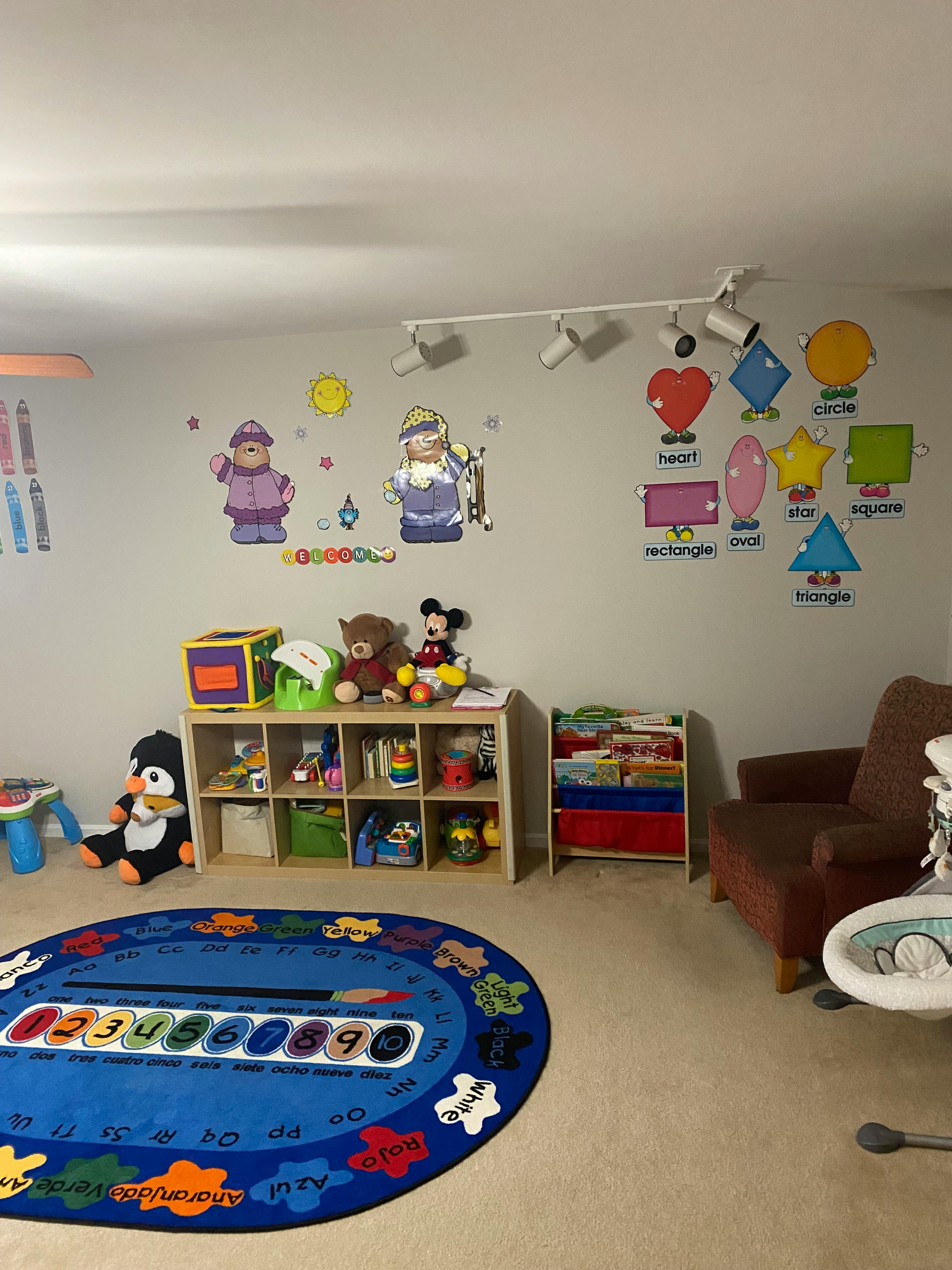Playroom with a blue rug, toy shelf, and wall decorations